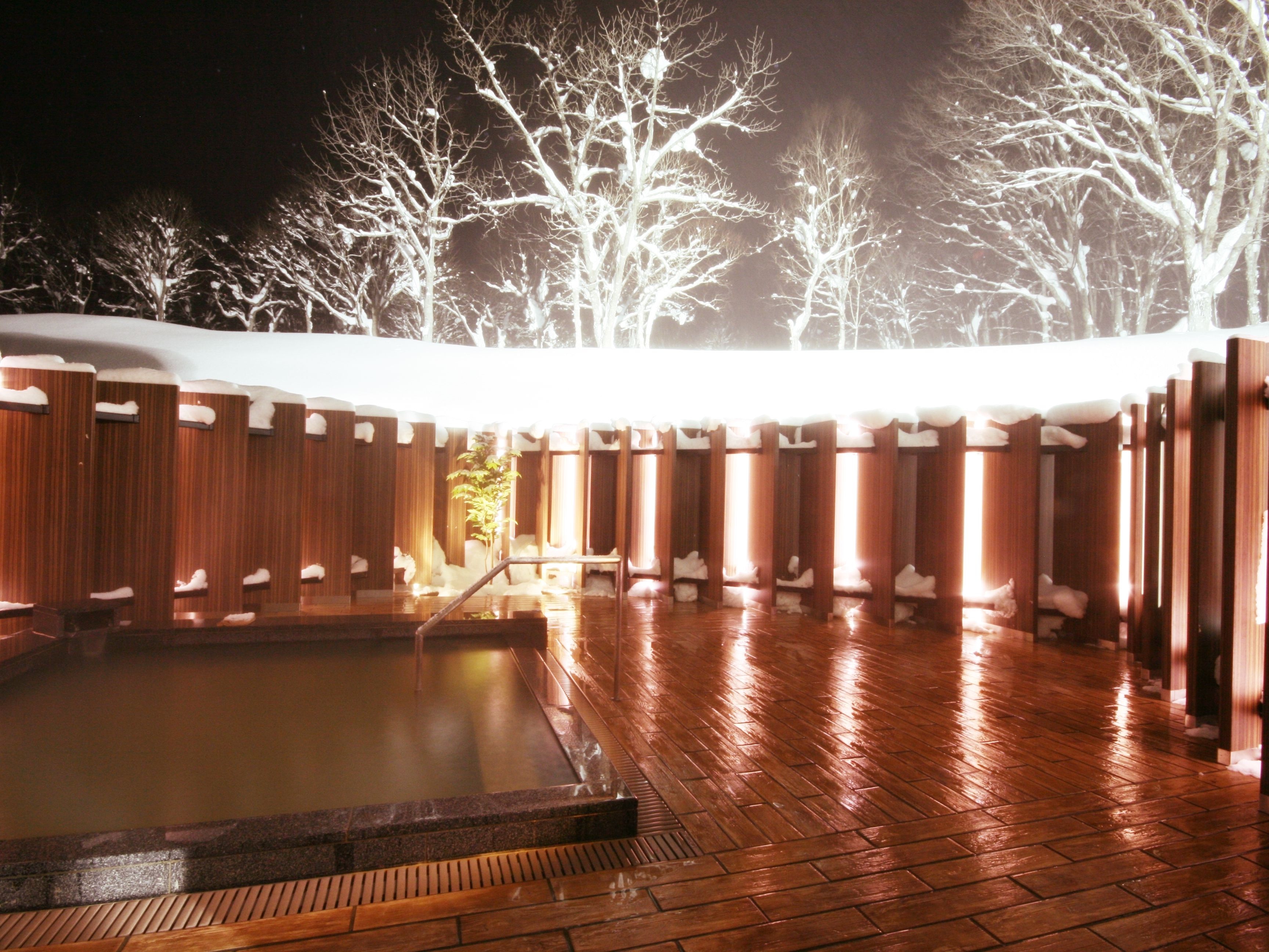 Uma área de spa em madeira com uma banheira de hidromassagem e bancos de madeira.