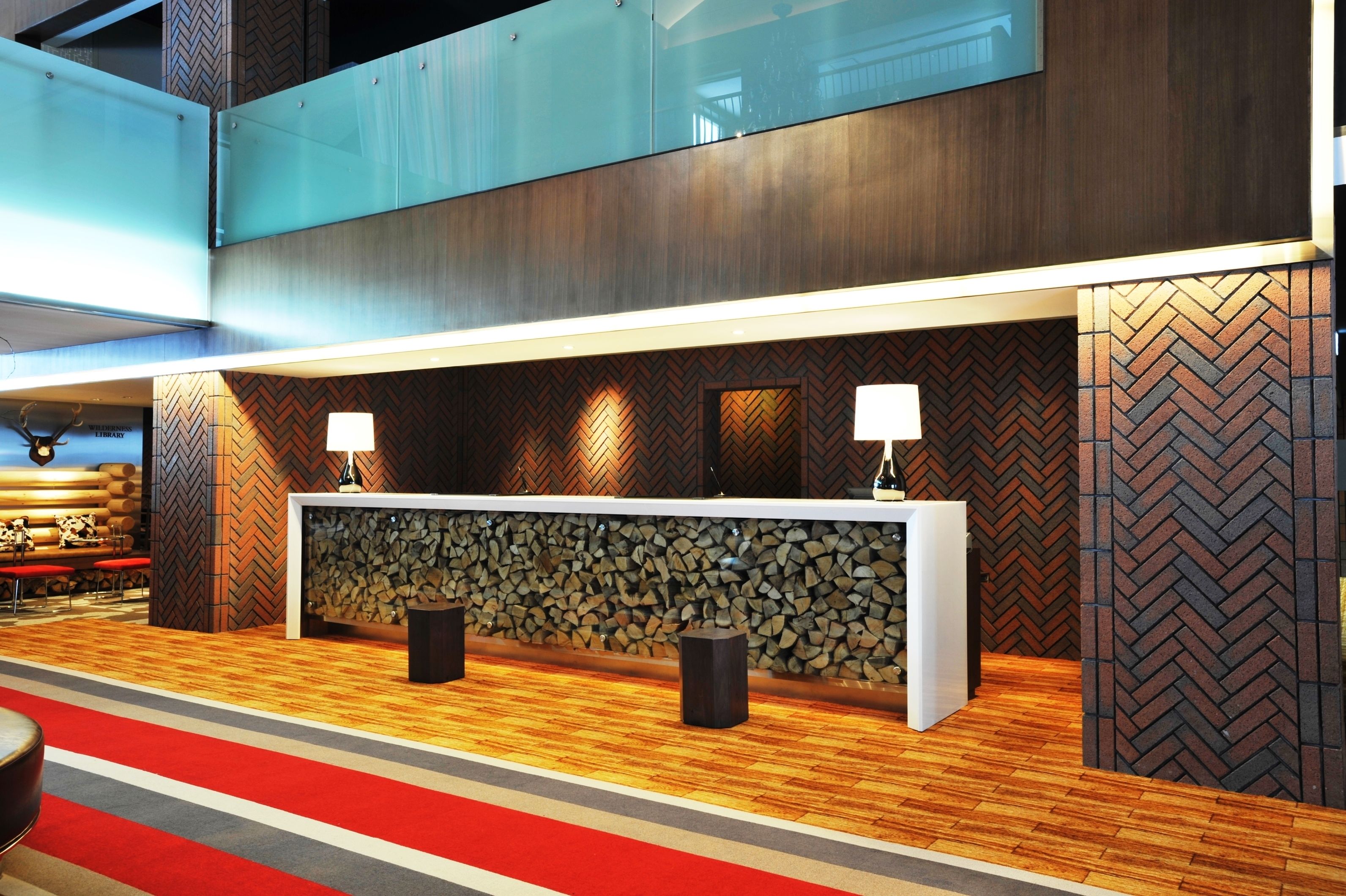 A reception area with a wooden herringbone wall, a stone wall, and a red carpet.