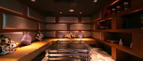 A modern interior with a sofa, a glass-top table, and shelves with decorative items.