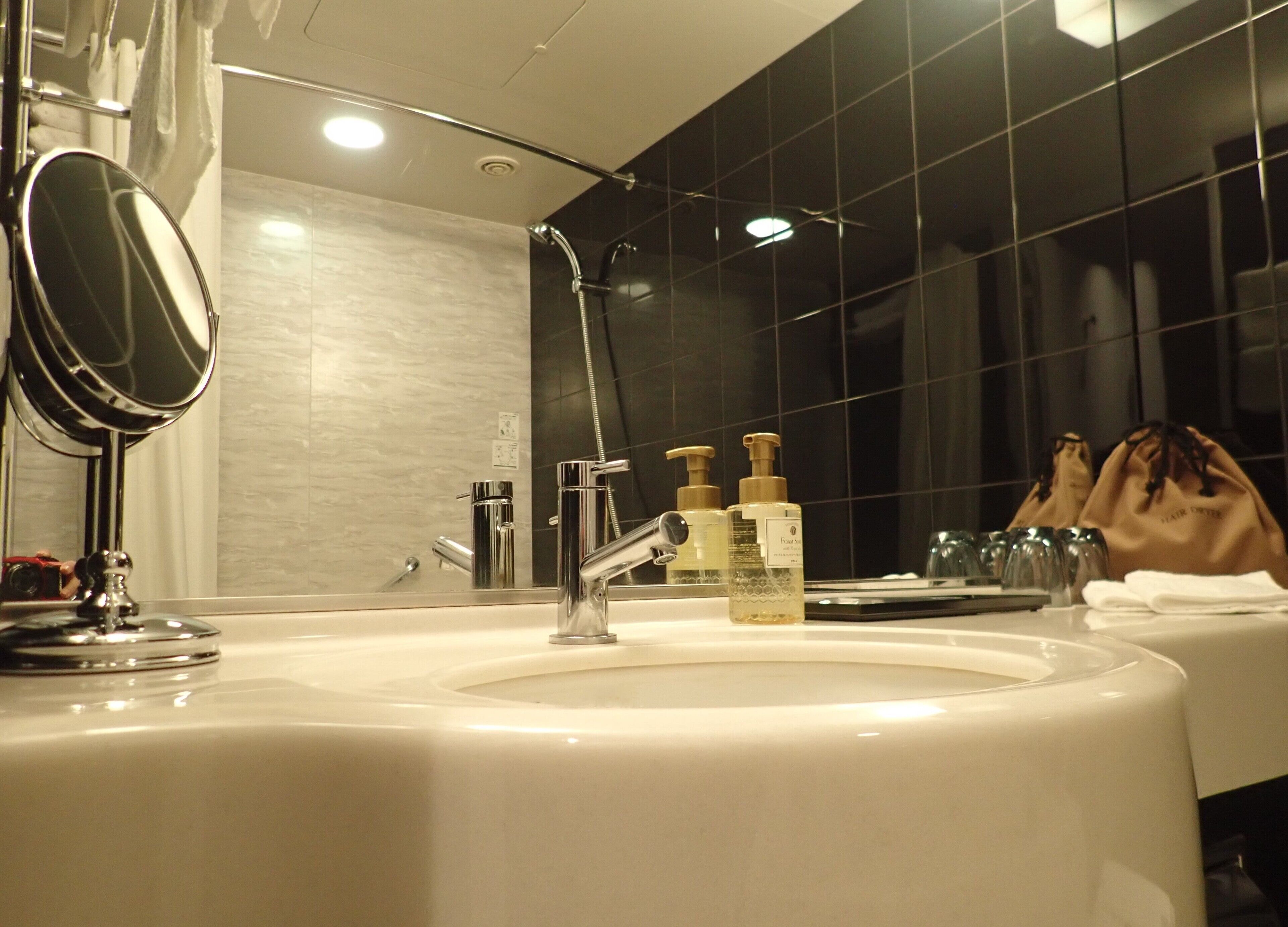 Un bagno moderno con uno specchio grande, un lavandino e due flaconi di shampoo.