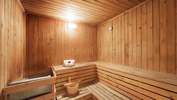 A wooden sauna with benches, a bench with a towel, and a wooden bucket.