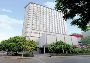 A modern hotel building with a prominent entrance and multiple flags.