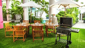 An outdoor patio with wooden tables and chairs, a grill, and umbrellas. - Hotel du Parc Hanoi (Hanoi)