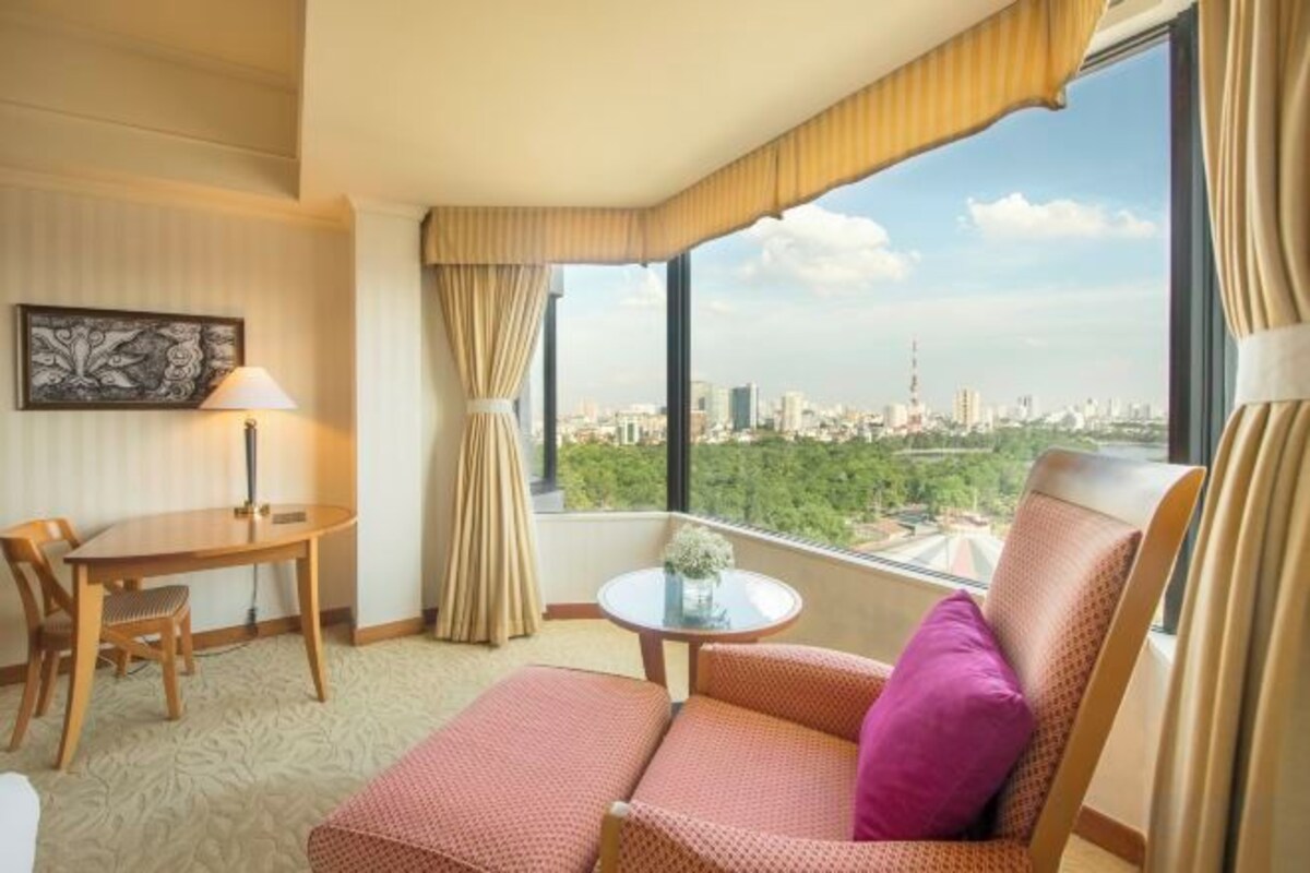 A hotel room with a balcony, a sofa, a table, and a chair.