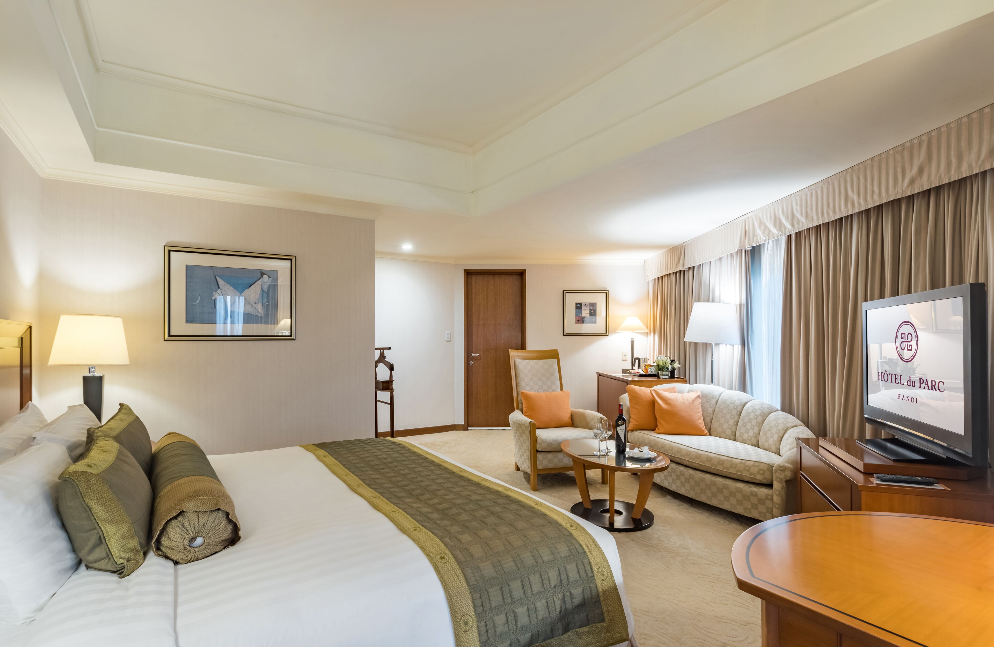 Una habitación de hotel con una cama grande, un sofá, una silla, un televisor y un escritorio.