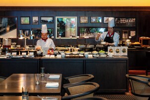 A buffet setup with multiple food stations and a chef preparing food.