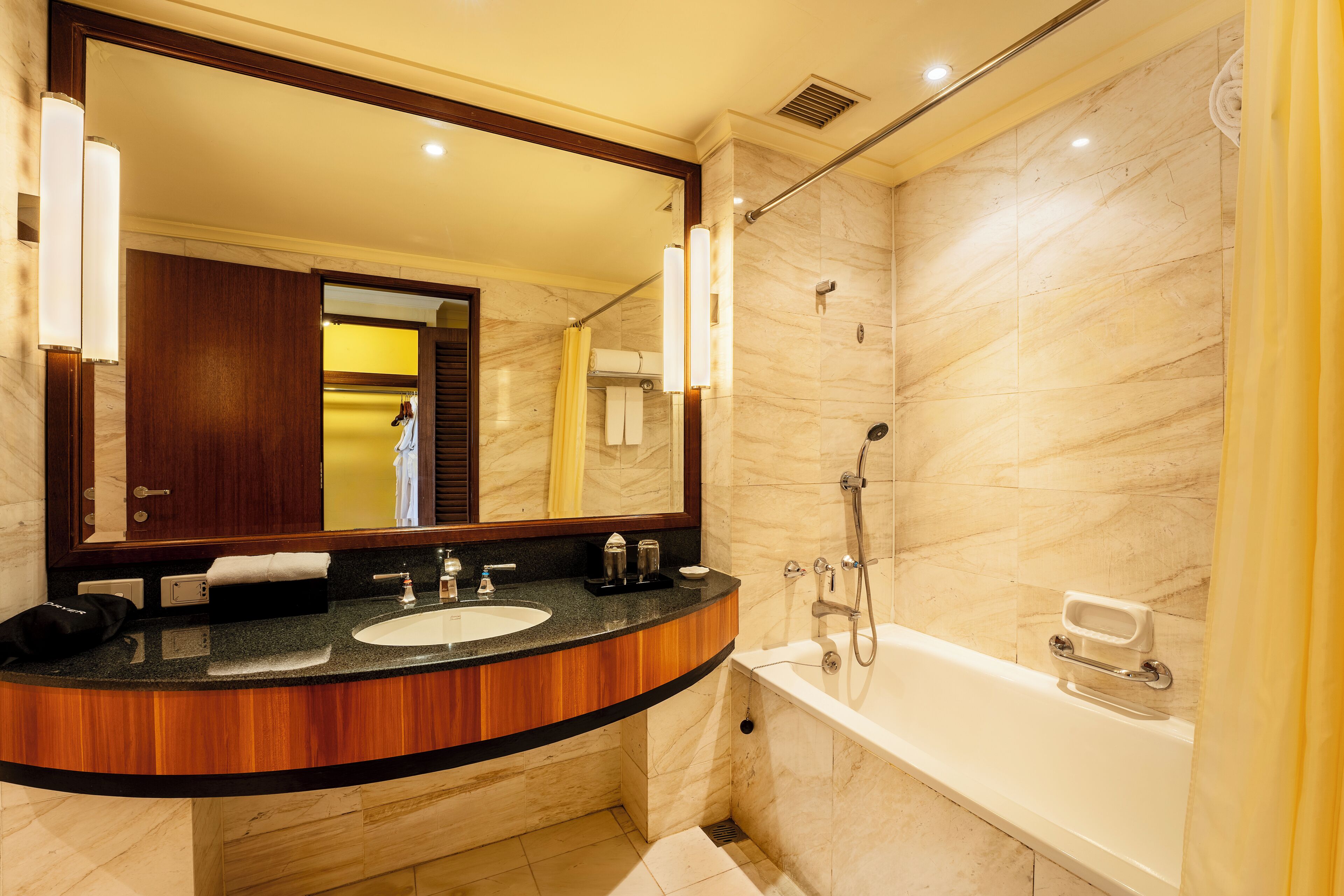 A bathroom with a marble shower, a bathtub, a sink with a vanity, and a large mirror.