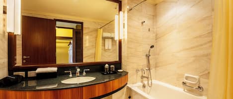 Un baño con ducha de mármol, bañera, lavabo con tocador y un espejo grande.