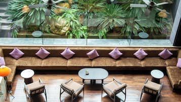A seating area with a sofa and chairs, a small table, and a view of indoor plants through a glass window.