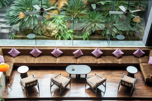 A seating area with a sofa and chairs, a small table, and a view of indoor plants through a glass window. - Hotel du Parc Hanoi (Hanoi)