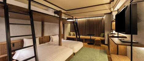 A hotel room with bunk beds, a desk with a flat-screen TV, and a seating area with curtains.