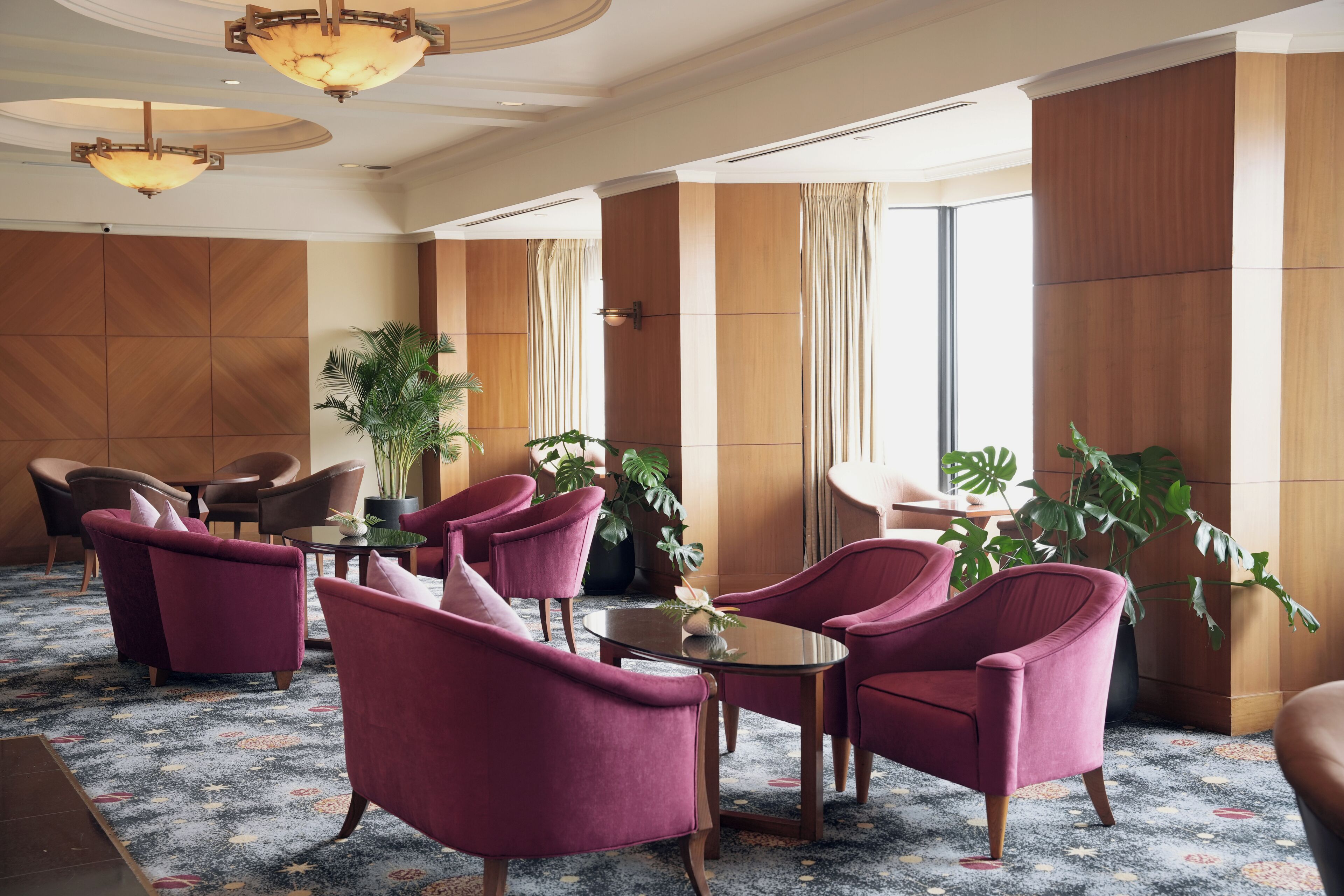 A lobby with seating, a chandelier, and large windows.