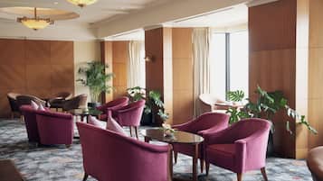 A lobby with seating, a chandelier, and large windows.