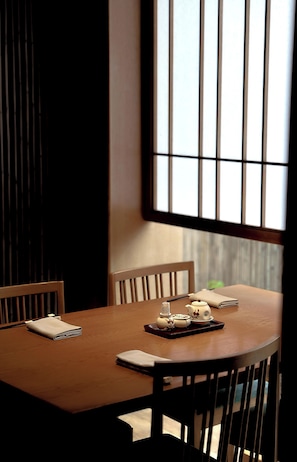 A dining table with chairs, a window with vertical blinds, and a tray with teapot and cups. - Hotel du Parc Hanoi (Hanoi)
