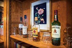 Una estantería de madera con varias botellas de whisky y un cuadro enmarcado con flores.