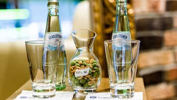 Three Gerolsteiner beer bottles, a glass carafe, and a glass with snacks on a wooden table.