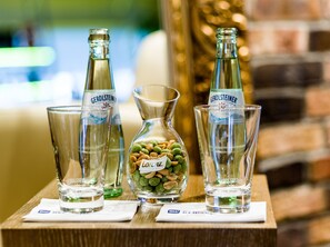 Tre Gerolsteiner ølflasker, en glas kande og et glas med snacks på et træbord.