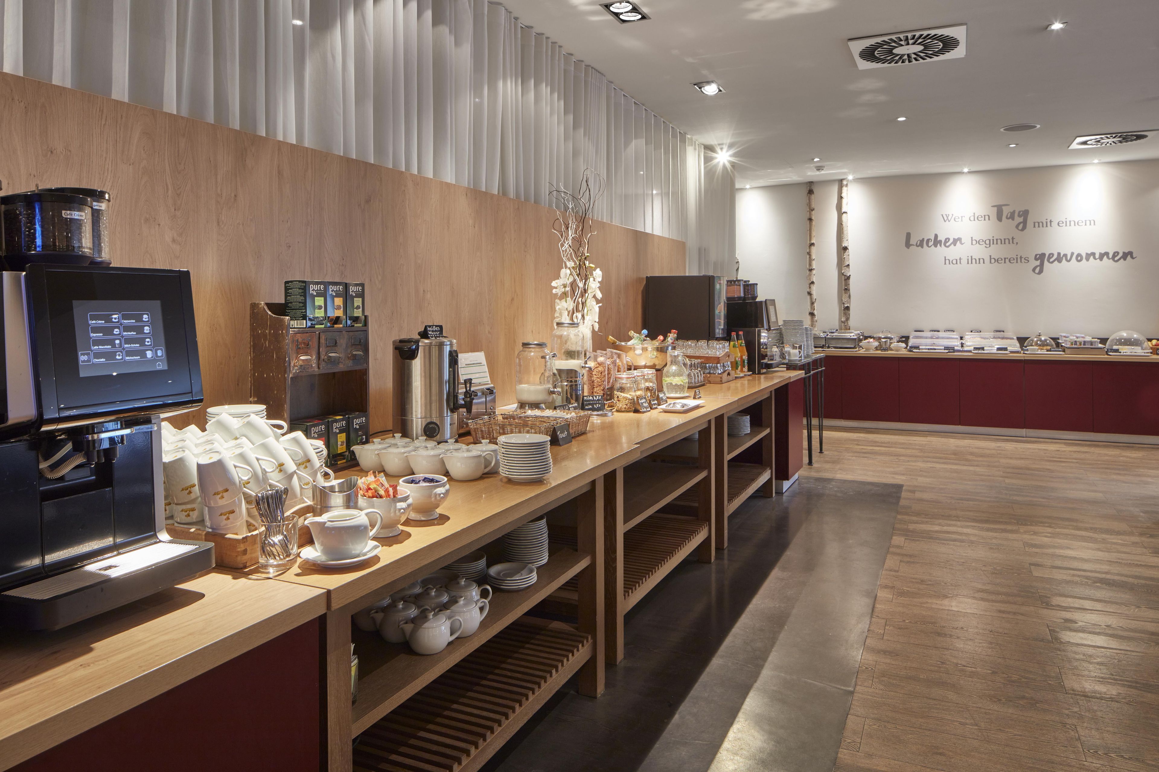 A cafe with a coffee machine, tea station, and various food items on display.