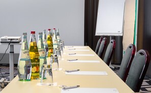 Een vergaderruimte met een lange tafel, meerdere flessen Gerolsteiner bier, glazen, pennen en naambordjes.