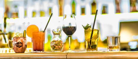 Un bar con diversas bebidas, incluyendo un vaso de cobre, un vaso con una rodaja de naranja, una botella de licor y una copa de vino.