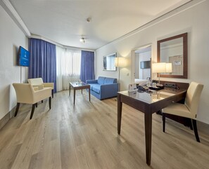 Een hotelkamer met een flatscreen televisie, een bank, een bureau met telefoon en een spiegel.