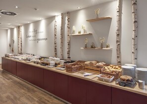 Een buffetopstelling met diverse gerechten en een bordje dat een ontbijtoptie aangeeft.