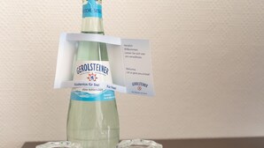 Une bouteille d’eau minérale Gerolsteiner avec un bouchon bleu et une étiquette attachée.