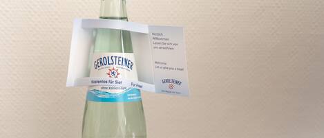 A Gerolsteiner mineral water bottle with a blue cap and a tag attached.
