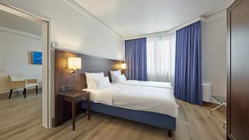 Ein Hotelzimmer mit einem großen Bett, Nachttischen, einem Schreibtisch und einem Sessel.