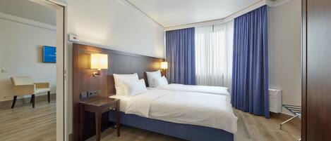 A hotel room with a large bed, bedside tables, a desk, and a chair.