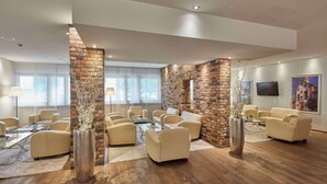 A spacious lounge area with leather sofas, a coffee table, and a brick accent wall.