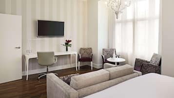 Ein Hotelzimmer mit einem Bett, einem Schreibtisch, zwei Sesseln, einem kleinen Tisch und einem Fernseher.