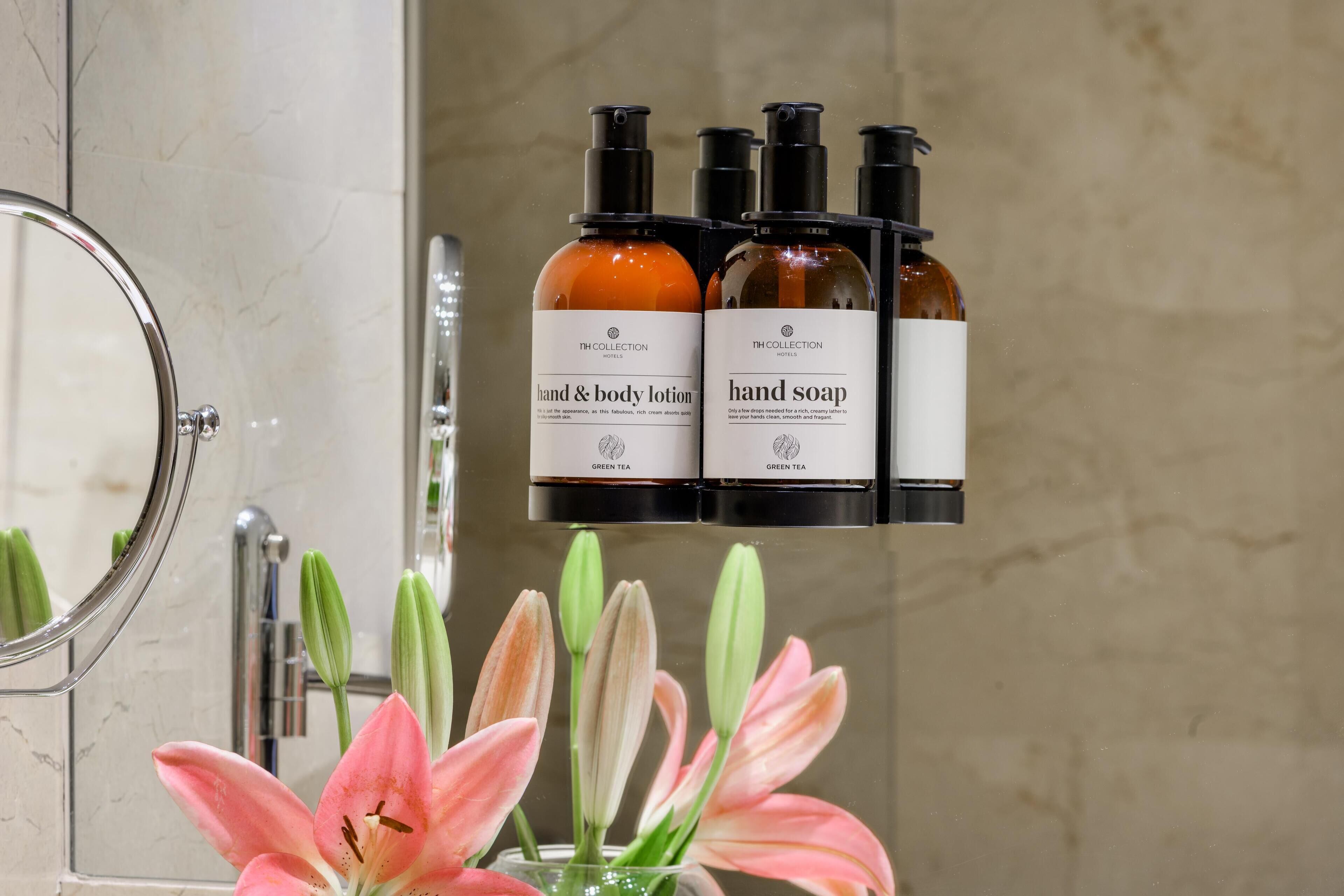 A bathroom with a hand and body lotion and hand soap dispenser on a shelf.
