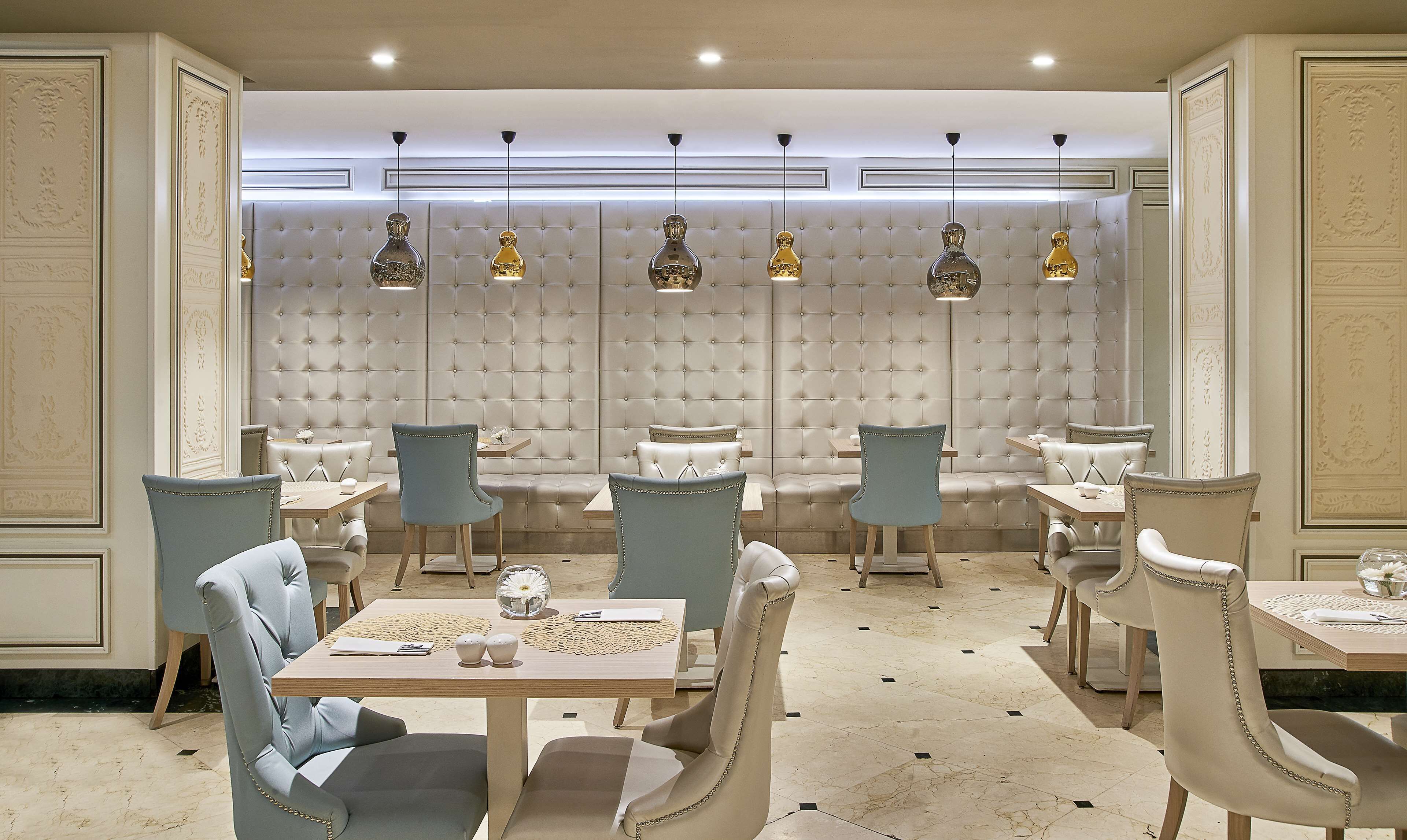 A dining area with a tufted wall, leather chairs, and pendant lighting.