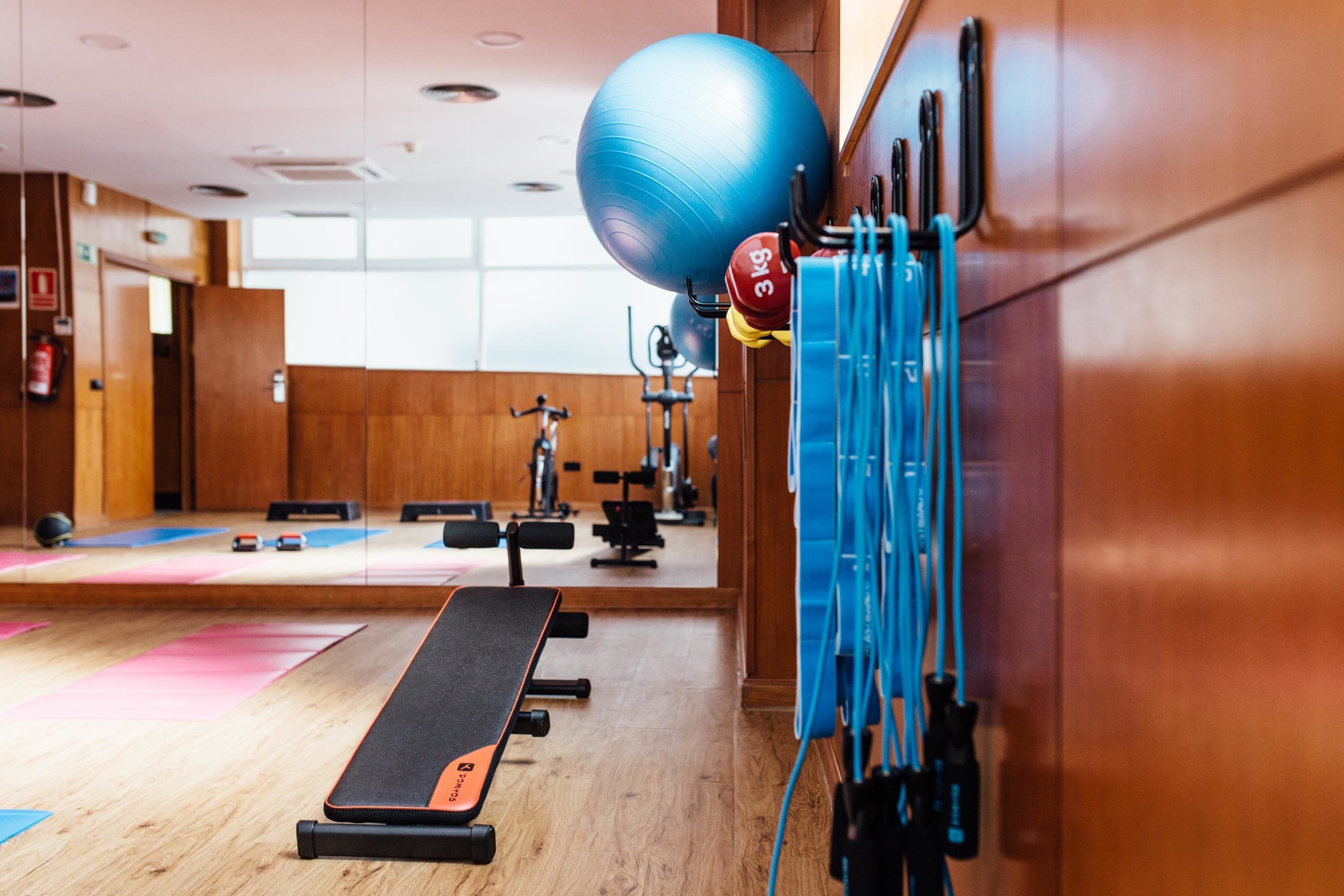 Ein Fitnessraum mit Trainingsgeräten, einem blauen Trainingsball und einer Bank.