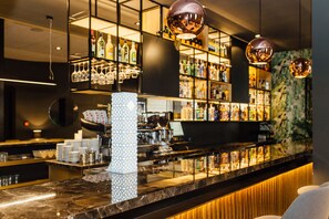 A bar area with shelves stocked with bottles, glasses, and a marble counter.