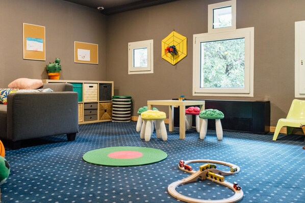 A children's playroom with a blue polka dot carpet, a play table, and various toys.