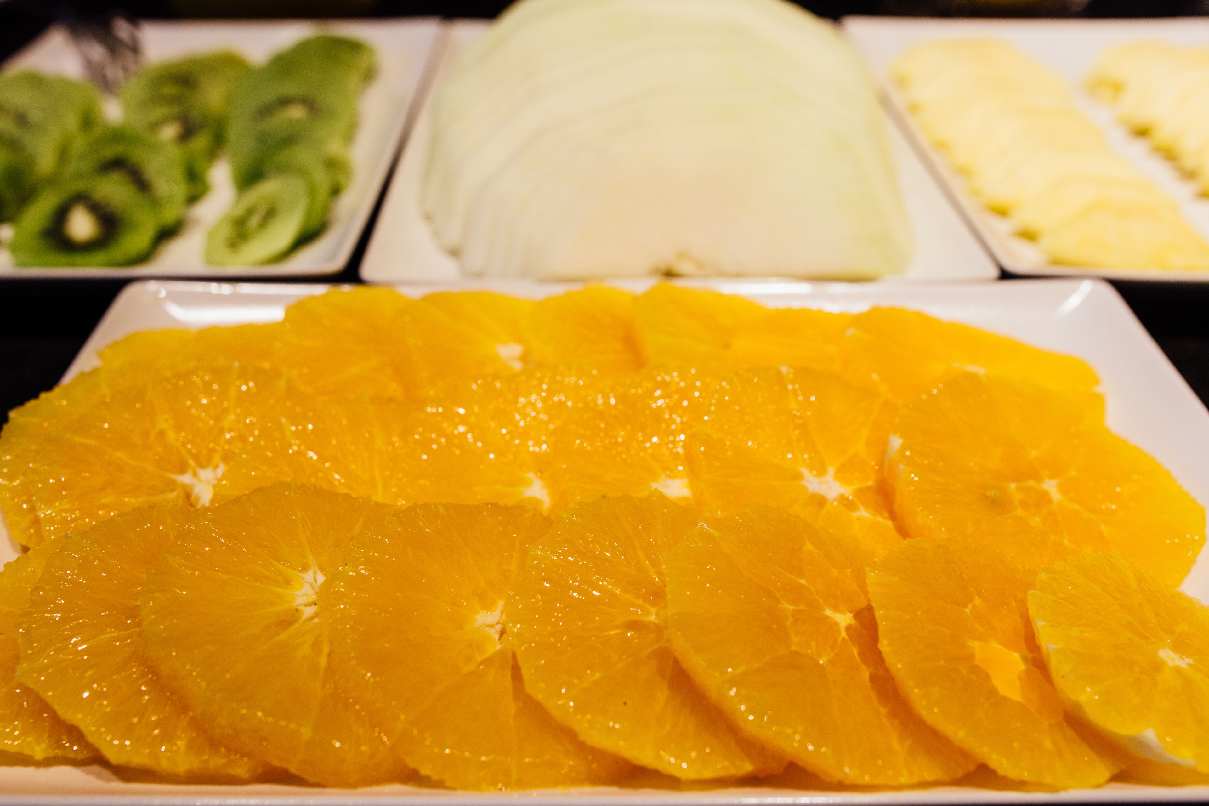Una bandeja de frutas con naranja, kiwi y melón en rodajas.