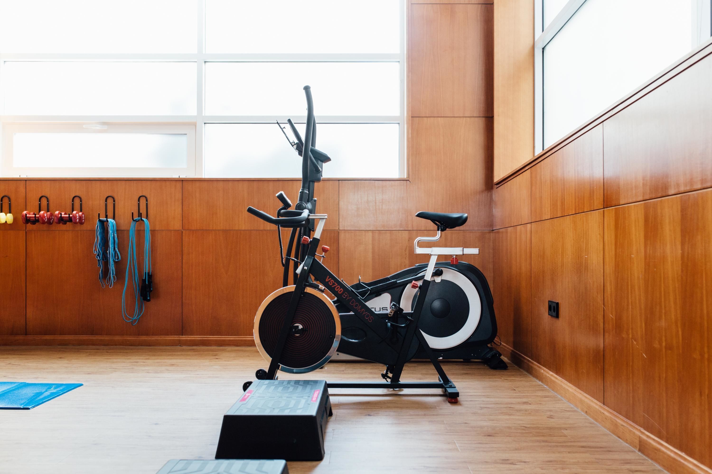 Una bicicleta estàtica en una habitació amb parets de fusta i un gran finestral.