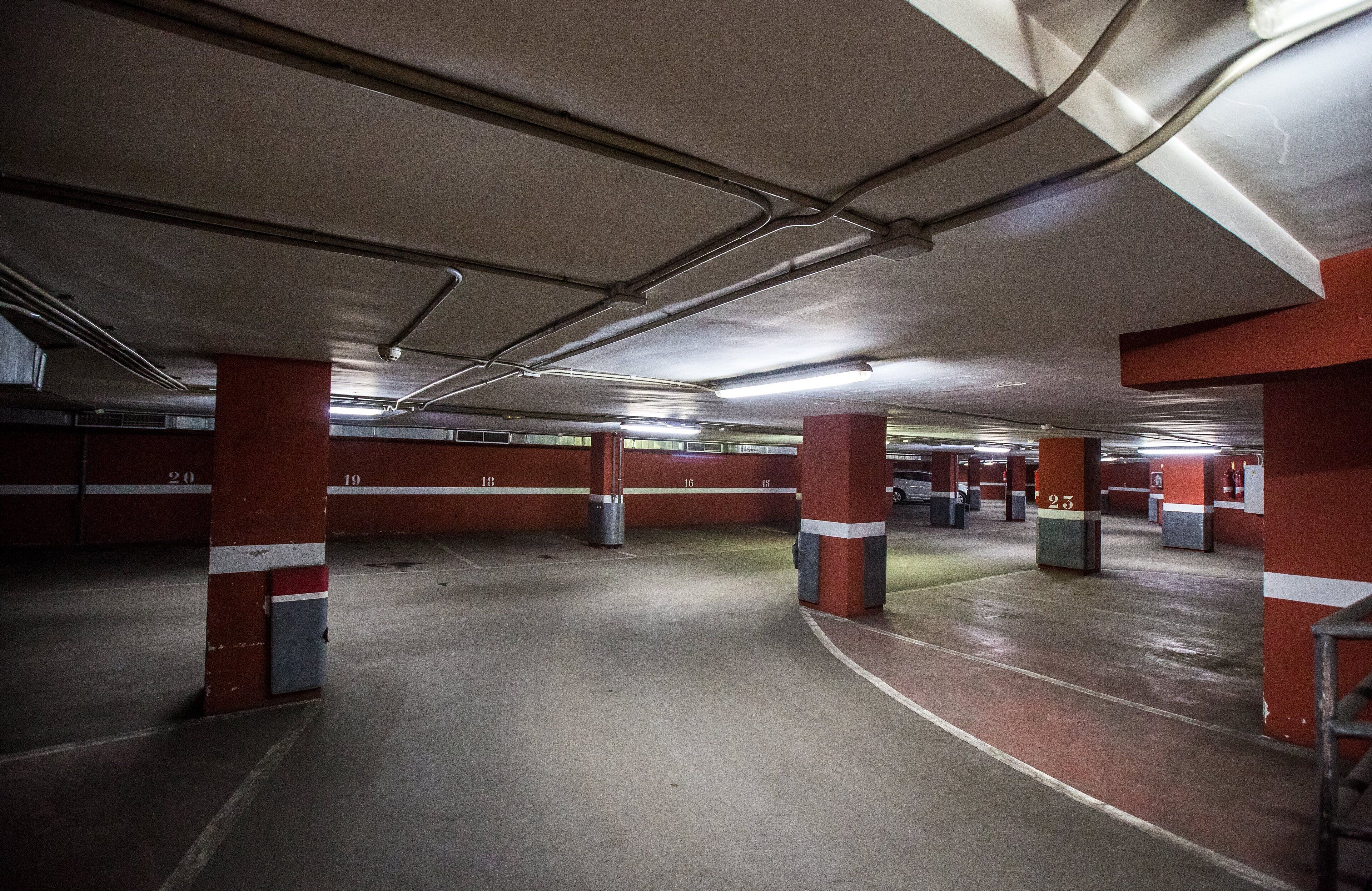An underground parking garage with red pillars and white numbers indicating parking spots.