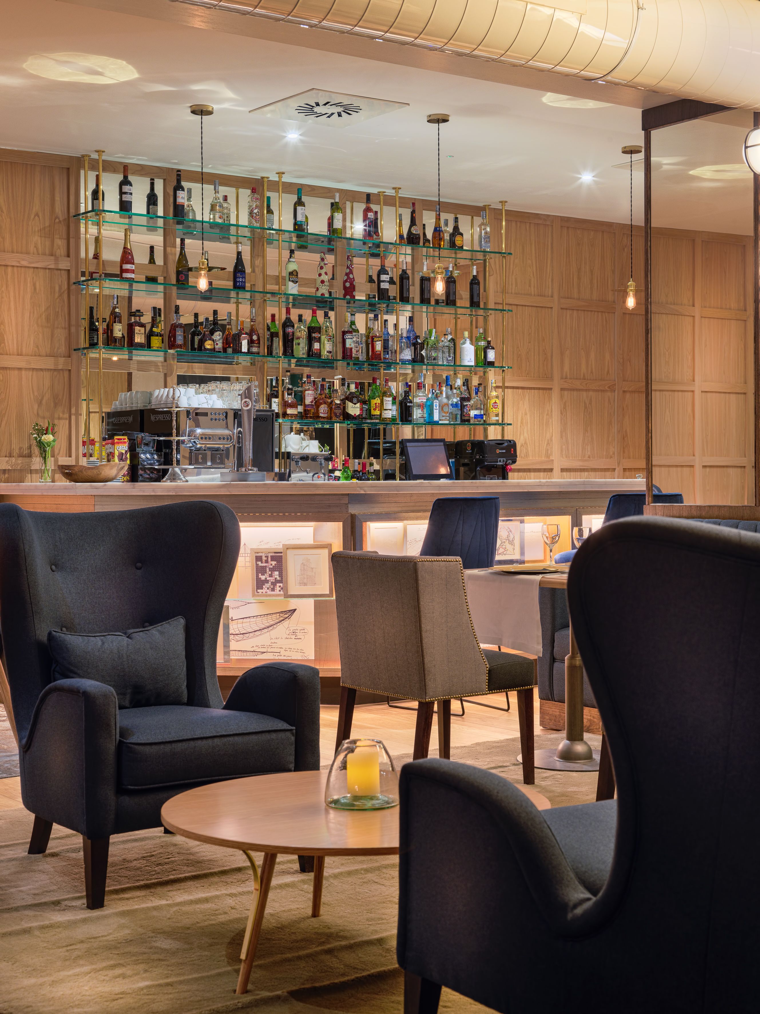 A bar area with multiple shelves of bottles, a coffee machine, and seating with a round table.