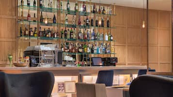 A bar area with multiple shelves of bottles, a coffee machine, and seating with a round table.