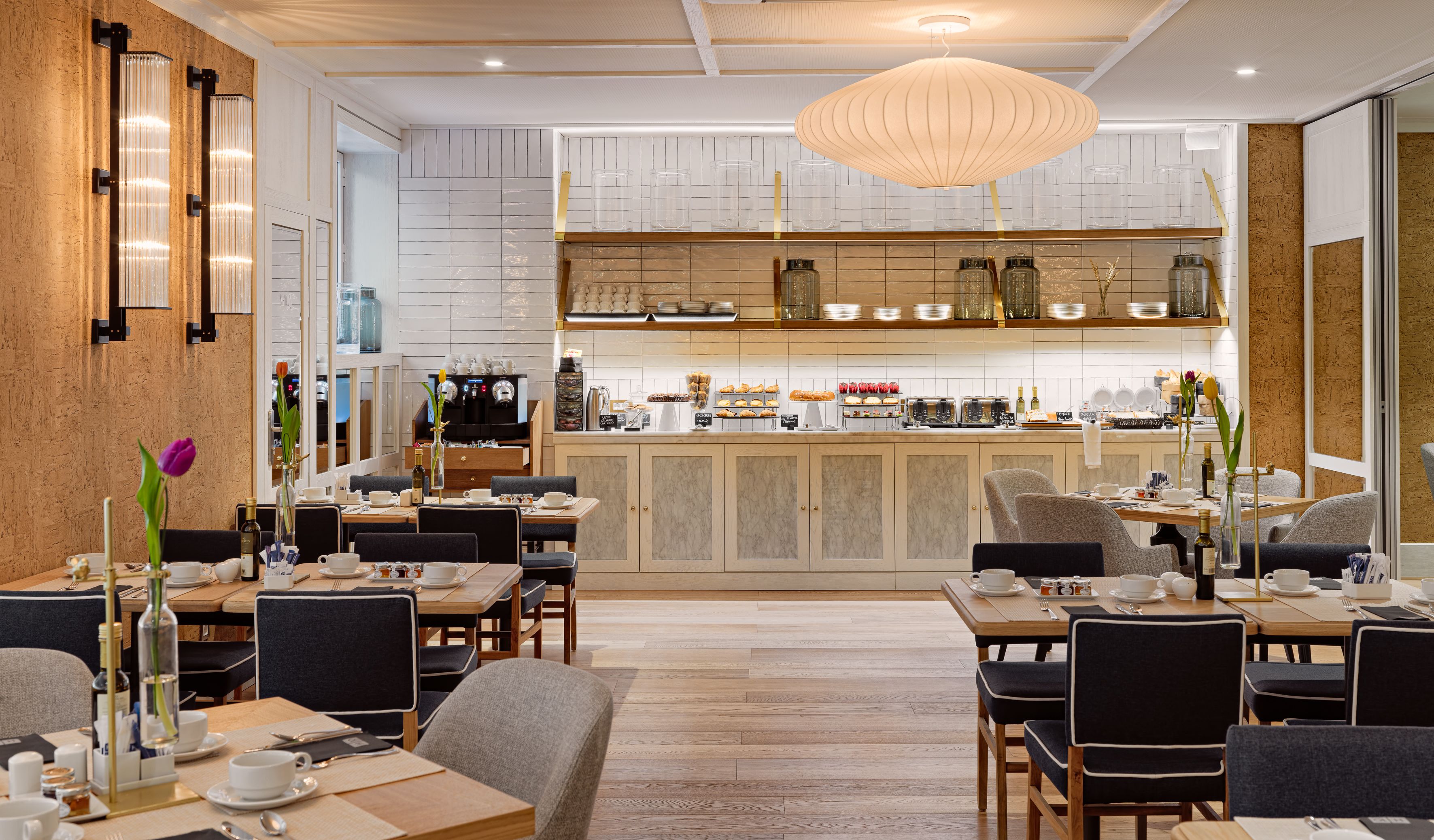 Un café moderno con suelo de madera, paredes con azulejos de mármol y una zona de bar central.