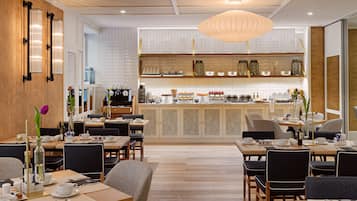 Un café moderno con suelo de madera, paredes con azulejos de mármol y una zona de bar central.