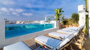 A rooftop pool area with lounge chairs and a city view. - H10 Puerta de Alcalá 4* Sup (Madrid)