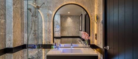 A modern bathroom with a glass-enclosed shower, a double sink vanity, and a large mirror.