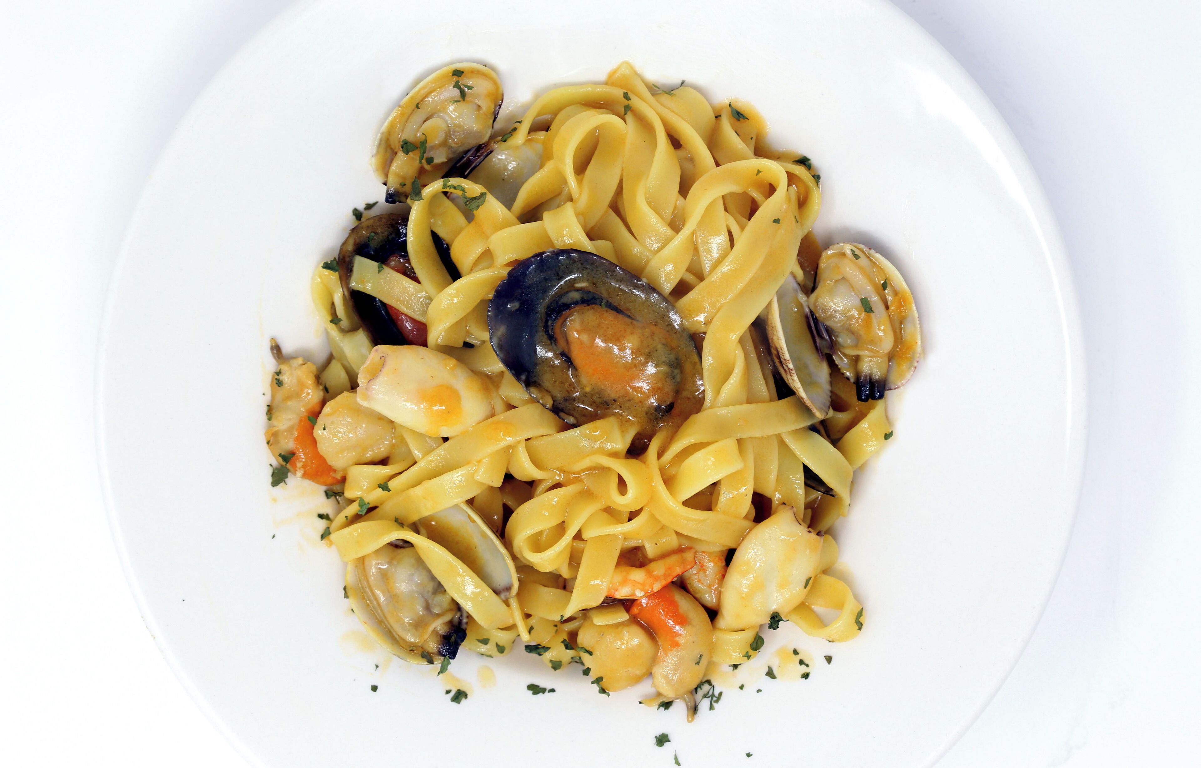 Un plato de pasta con mejillones y verduras.