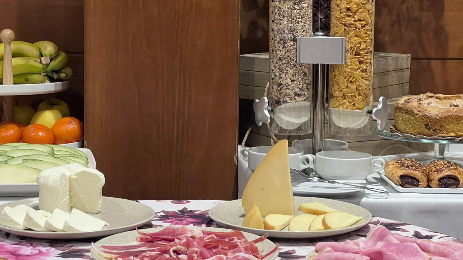 A buffet with various food items including cheese, fruits, and pastries.