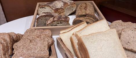 A variety of breads and rolls in wooden trays on a table.