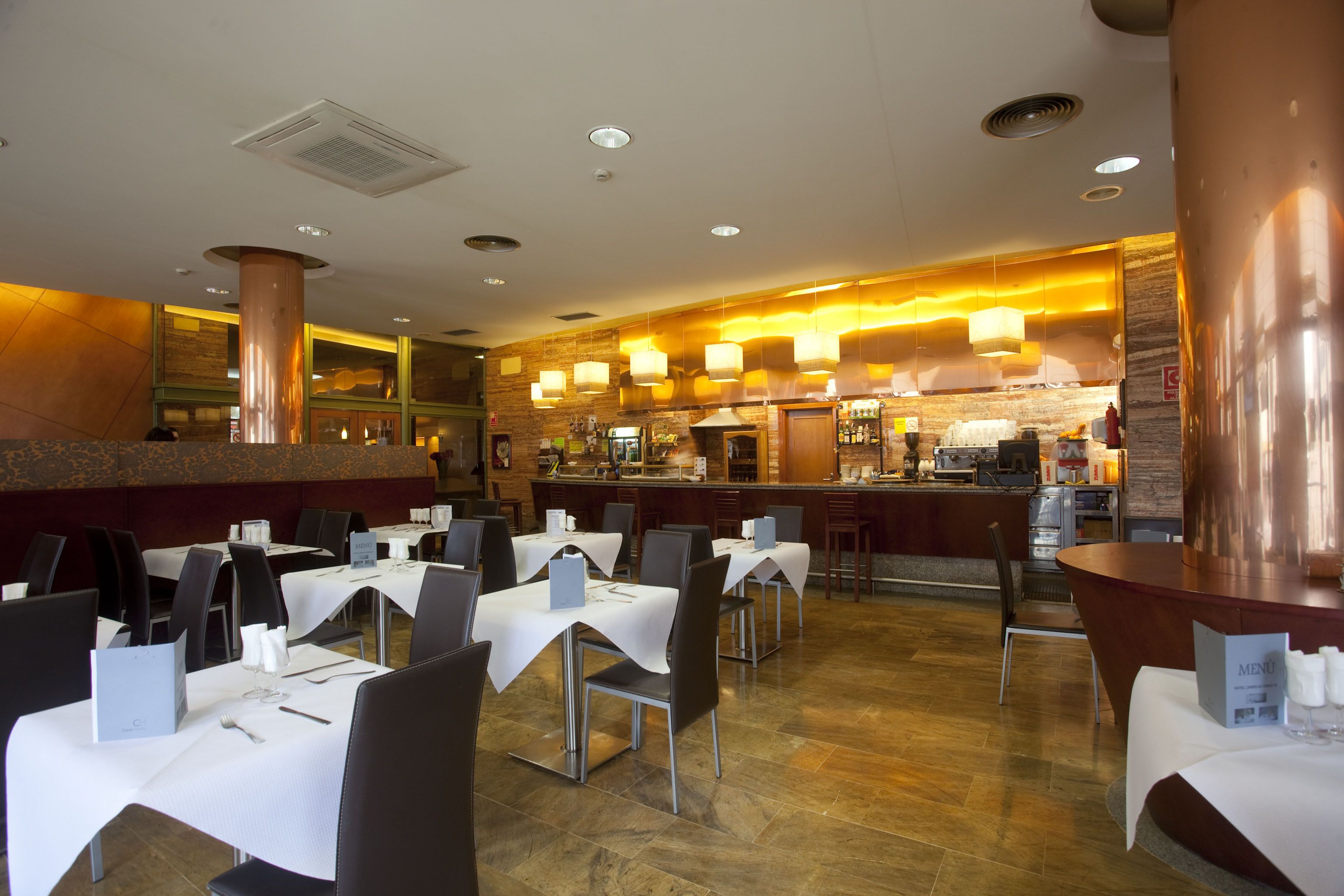 Een restaurant met gedekte tafels, een bar en een keuken op de achtergrond.